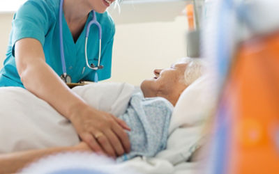 Nurse helping elderly incontinent patient in bed