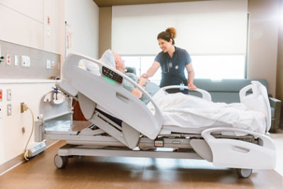 Nurse communicating with patient in a hospital bed