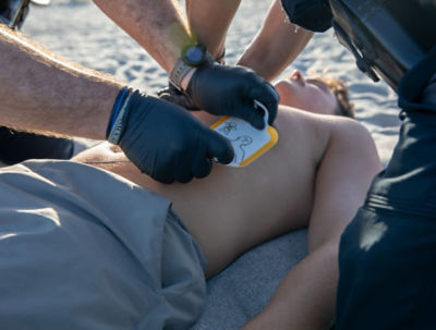 Paramedics applying the LIFEPAK CR2 pads to a young man on the beach.