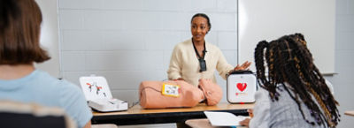 An instructor explaining how to use an AED to young students.