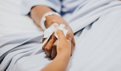 Hospital patient holding hand with caregiver