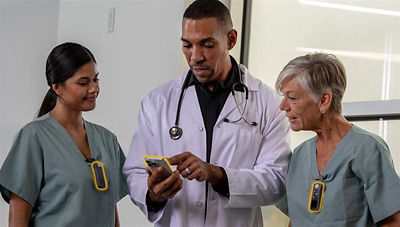 doctor pointing to mobile device beside two nurses wearing badges