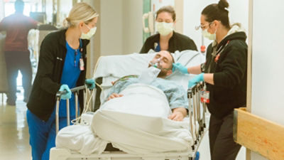 nurses wearing masks attending to patient on stretcher