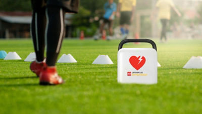 Soccer player stands next to a LIFEPAK CR2 AED on the field