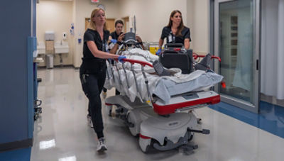 Nurses rushing patient down hospital hallway in a Stryker stretcher while using LIFEPAK 35 monitor/defibrillator and LUCAS chest compression system