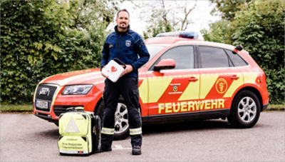 EMT stands outside emergency vehicle holidng a LIFEPAK CR2 AED 