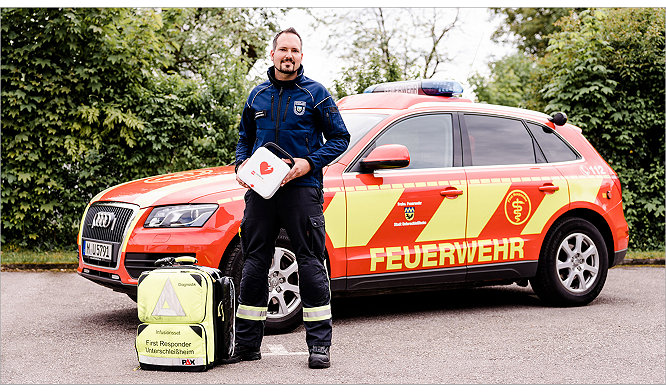 EMT stands outside emergency vehicle holidng a LIFEPAK CR2 AED 