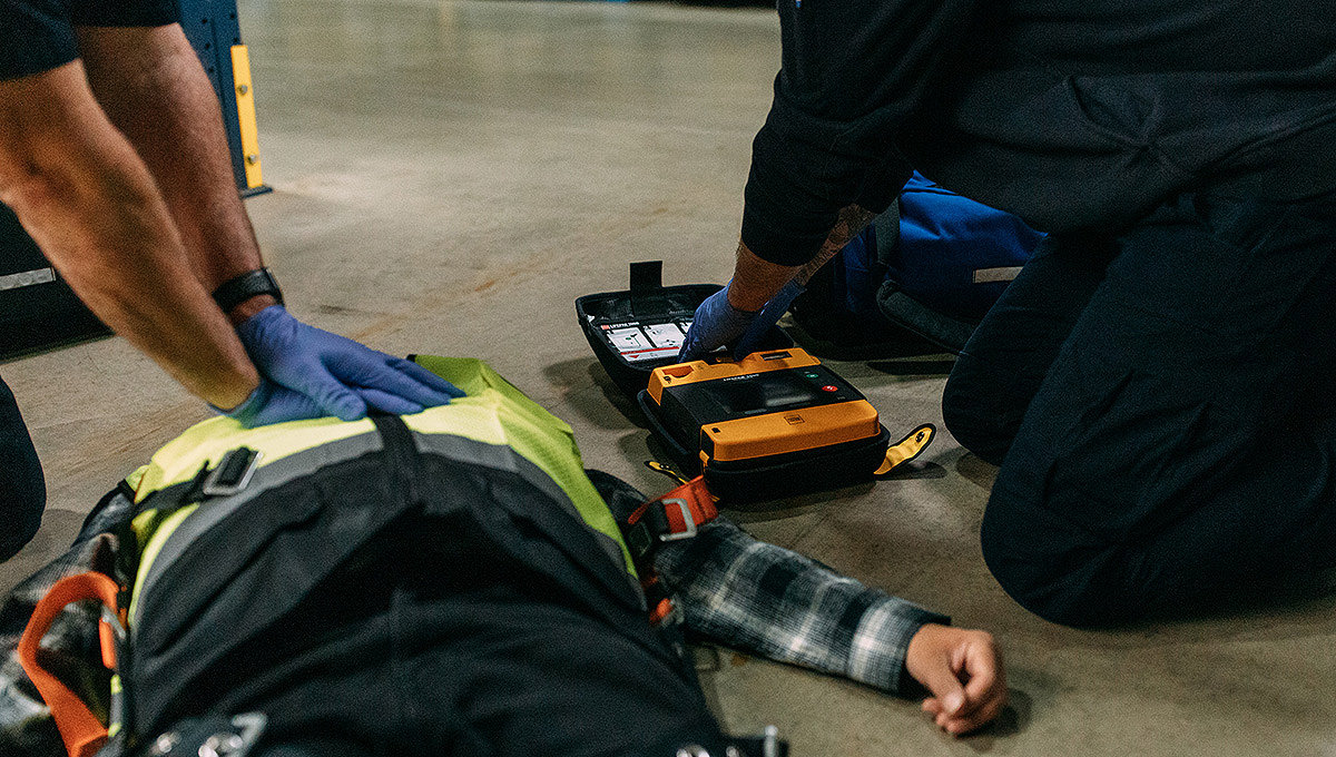 Homme couché sur le sol avec le défibrillateur LIFEPAK 1000 placé sur sa poitrine