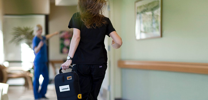 Un profesionist din domeniul medical aleargă cu un defibrilator LIFEPAK 1000