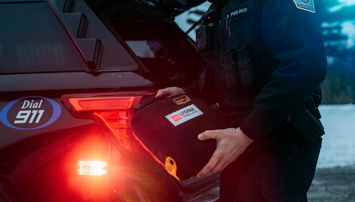 Police officer removes a LIFEPAK 100 AED from the back of his patrol vehicle 