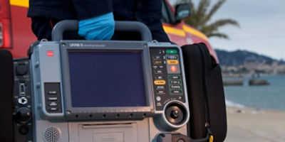 Profissional de serviços de emergência a transportar o monitor/desfibrilhador LIFEPAK 15