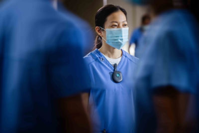 Female Critical Care Nurse masked up and wearing a Vocera Minibadge on her scrubs