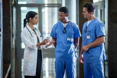 Doctors discuss patient in the hospital hallway while wearing Vocera Minibadges