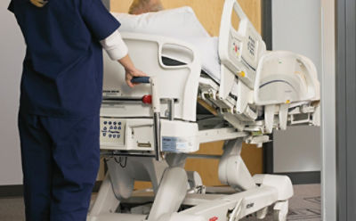 Caregiver using the Zoom Motorized Drive System on Stryker's InTouch critical care bed