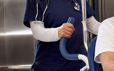 A nurses uses the BackSmart push handles on the Prime TC hospital transport wheelchair
