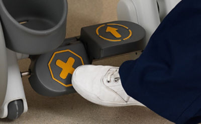 A nurse engages the one-touch central brake on the Prime TC transport wheelchair