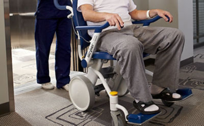 Um prestador de cuidados empurra o paciente na cadeira de transporte Prime TC da Stryker