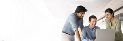 Business professionals collaborating in a modern office setting, reviewing ProAssure service details on a laptop