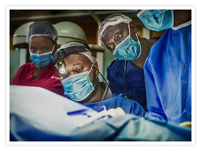 Dr. Clovis Baramburiye performs surgery while surgical residents observe in Rwanda, Africa