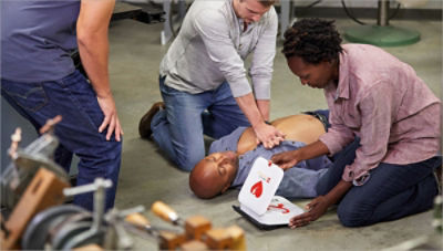 Co-workers helping colleauge suffering from sudden cardiac arrest by giving CPR and using an AED 