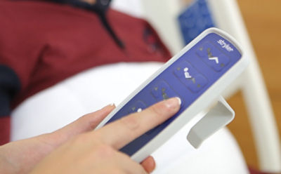 Close-up of caregiver pressing button on the remote control on Stryker's SV2 hospital bed