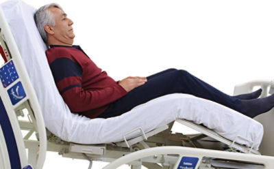 Im SV2-Krankenhausbett von Stryker liegender Mann mit Rückenlehne in Sitzposition