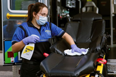 EMS professional spraying SideKick on a cot