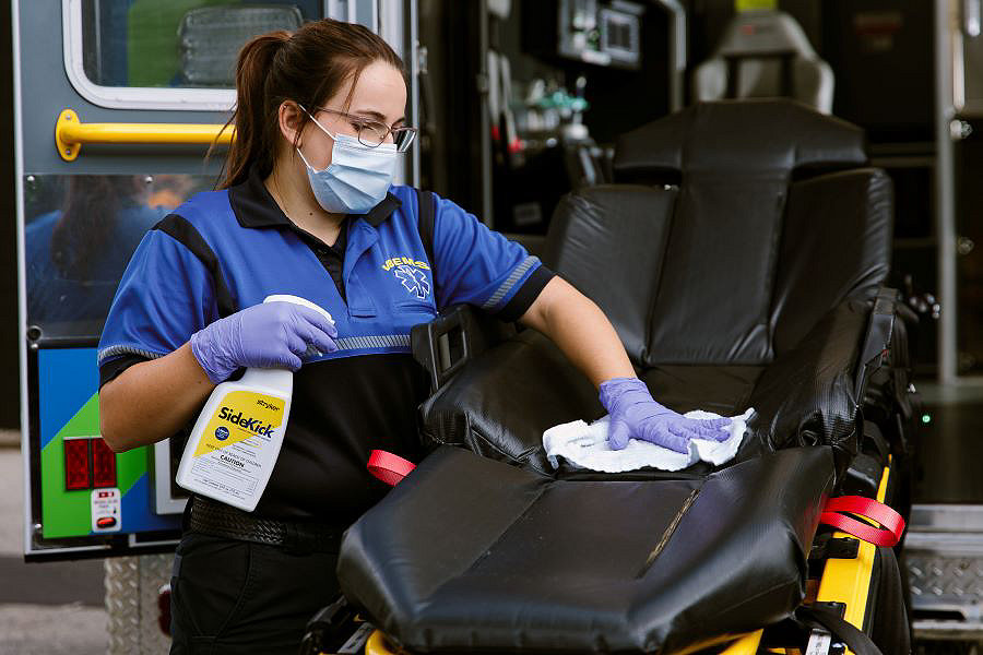 EMS professional spraying SideKick on a cot