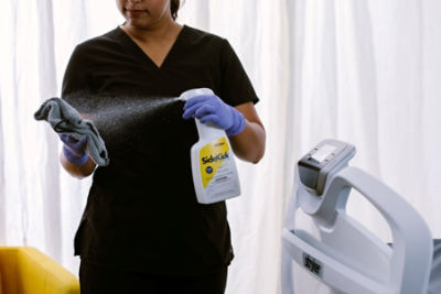 Healthcare professional spraying SideKick on a towel