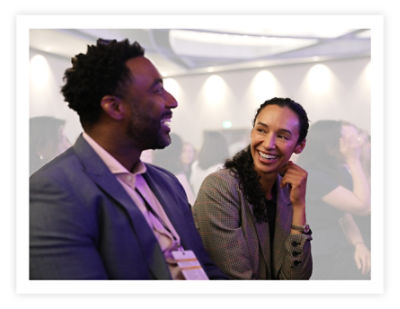 Dois funcionários da Stryker sorrindo um para o outro e conversando na conferência anual DE&amp;I