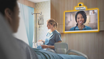 patient in bed looking at monitor with nurse in background