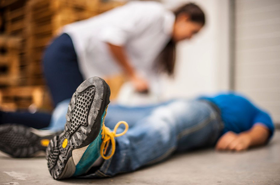 Sudden cardiac arrest victim laying on the floor with a bystander kneeling besides them 
