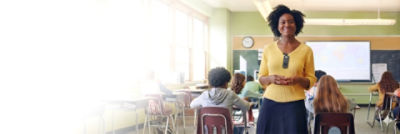 teacher wearing Sync Badge is standing in classroom with students behind her