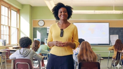 teacher wearing Sync Badge is standing in classroom with students behind her