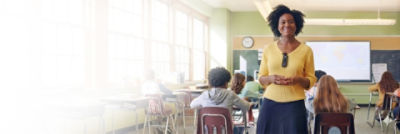 teacher wearing Sync Badge is standing in classroom with students behind her