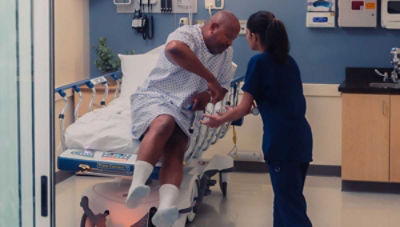 nursing assisting patient climbing out of hospital bed. 