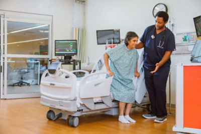 nurse helping patient out of hospital bed