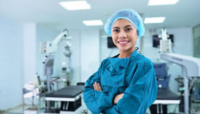 nurse wearing scrubs smiling and standing in operating room with arms crossed