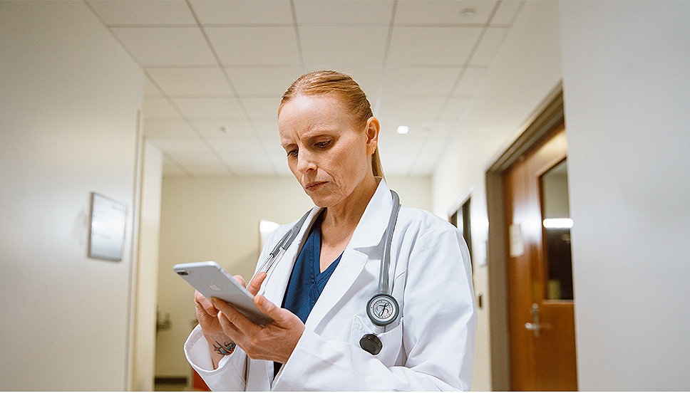 A doctor reviews patient information on her phone 