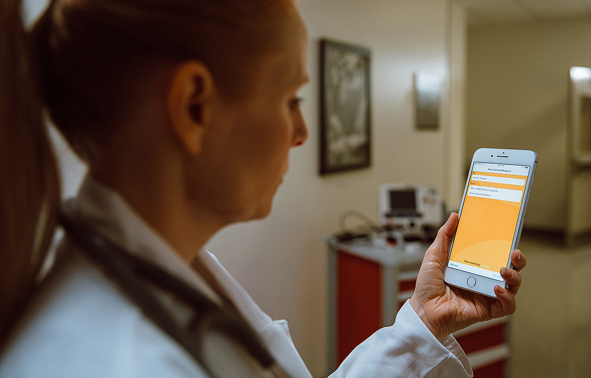 Un medic utilizează aplicația pentru telefoane inteligente Stryker LIFENET Consult pe dispozitivul său mobil.