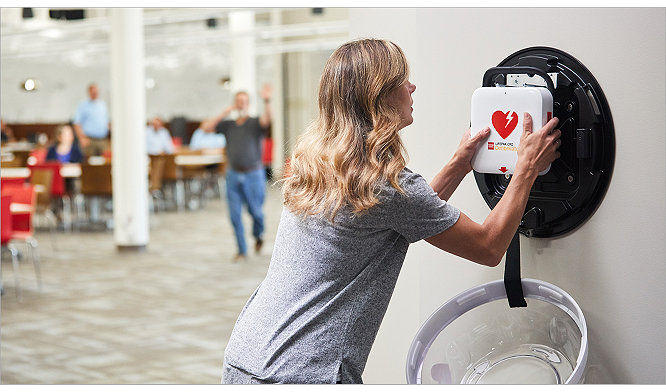 Woman grabbing an AED for use in an office setting 