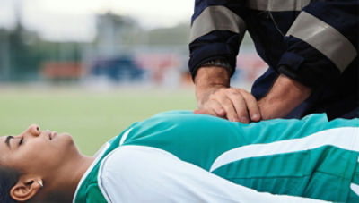 Athletic trainer giving CPR to athlete