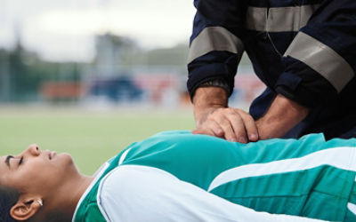 Athletic trainer giving CPR to athlete