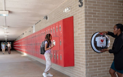 Teacher accessing a LIFEPAK CR2 AED in a school hallway