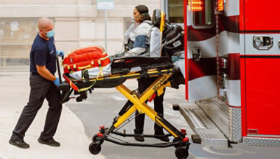 EMT loading patient on stretcher into emergency vehicle