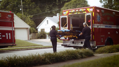 EMTs removing powered ambulance cot from an ambulance 