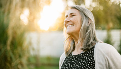 A woman smiles with joy after receiving treatment for vertebral compression fractures and reclaiming her quality of life