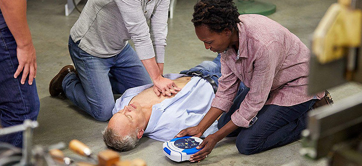 Man performing CPR on man lying on ground