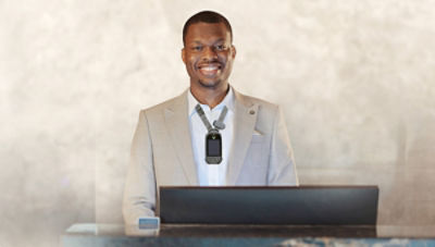 Hotel guest services standing at front desk wearing Vocera Smartbadge