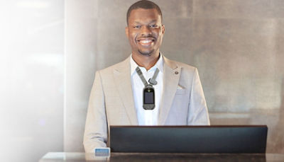 hotel guest services standing at front desk wearing Vocera badge